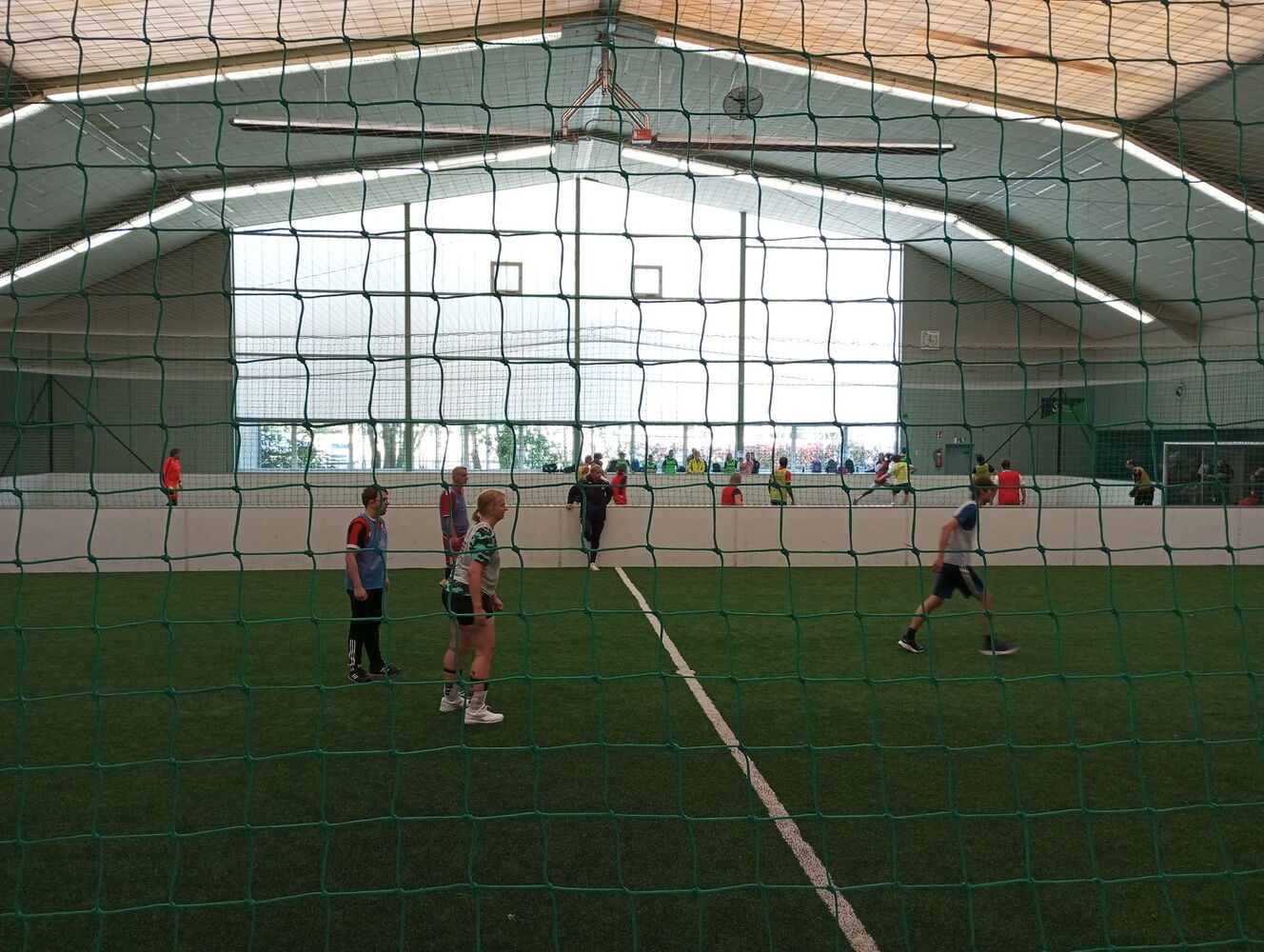 Durch das Netz fotografiert, sind 4 Spielende zu sehen, die alle in die gleiche Richtung schauen und sich bewegen.